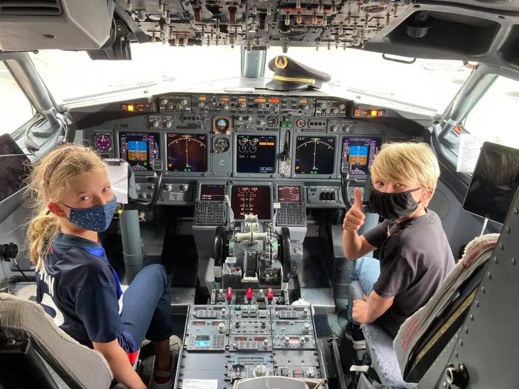 Two children posing for a pic in the airplane cockpit area on their training session