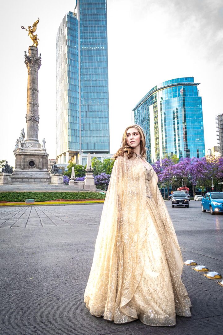 A woman in a sparkly gown posing near a statue