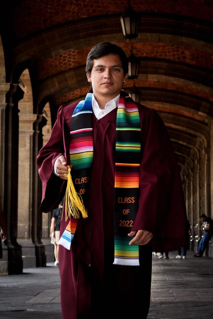 Young man in a maroon toga with the graduation cap one