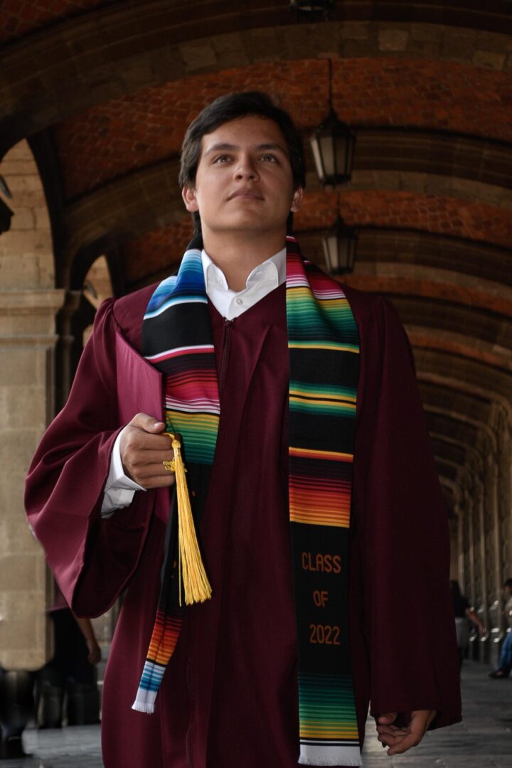 A young man wearing a maroon toga and multicolored scarf