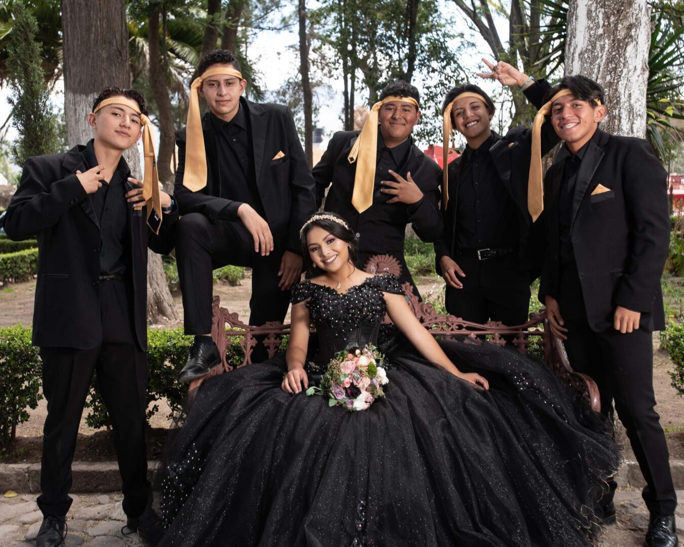 A young lady in a black gown and young men with neckties on their heads