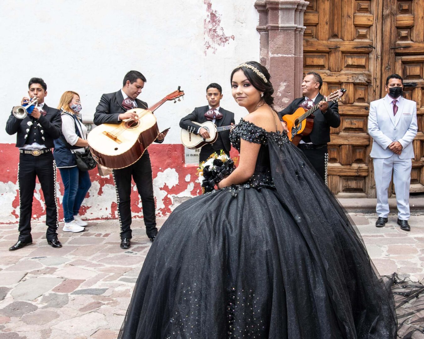 A young woman wearing a black gown and a mariachi band