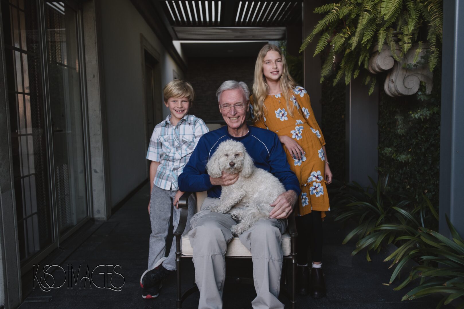 A man with a dog on his lap and a boy and girl standing beside him