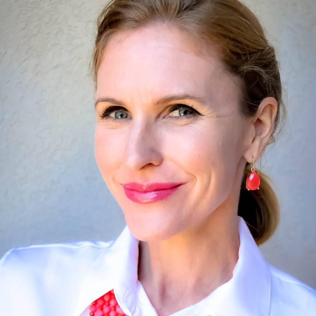 A headshot of a woman wearing bright red earrings