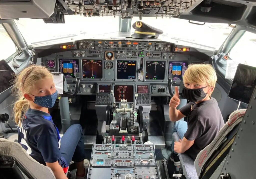 Two children posing for a pic in the airplane cockpit area on their training session